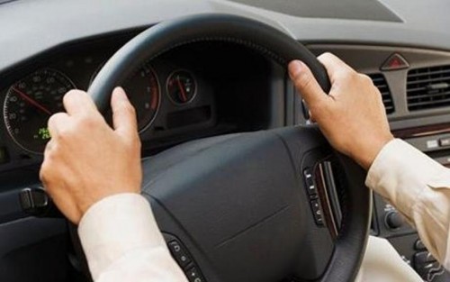 Close up of man's hands on steering wheel