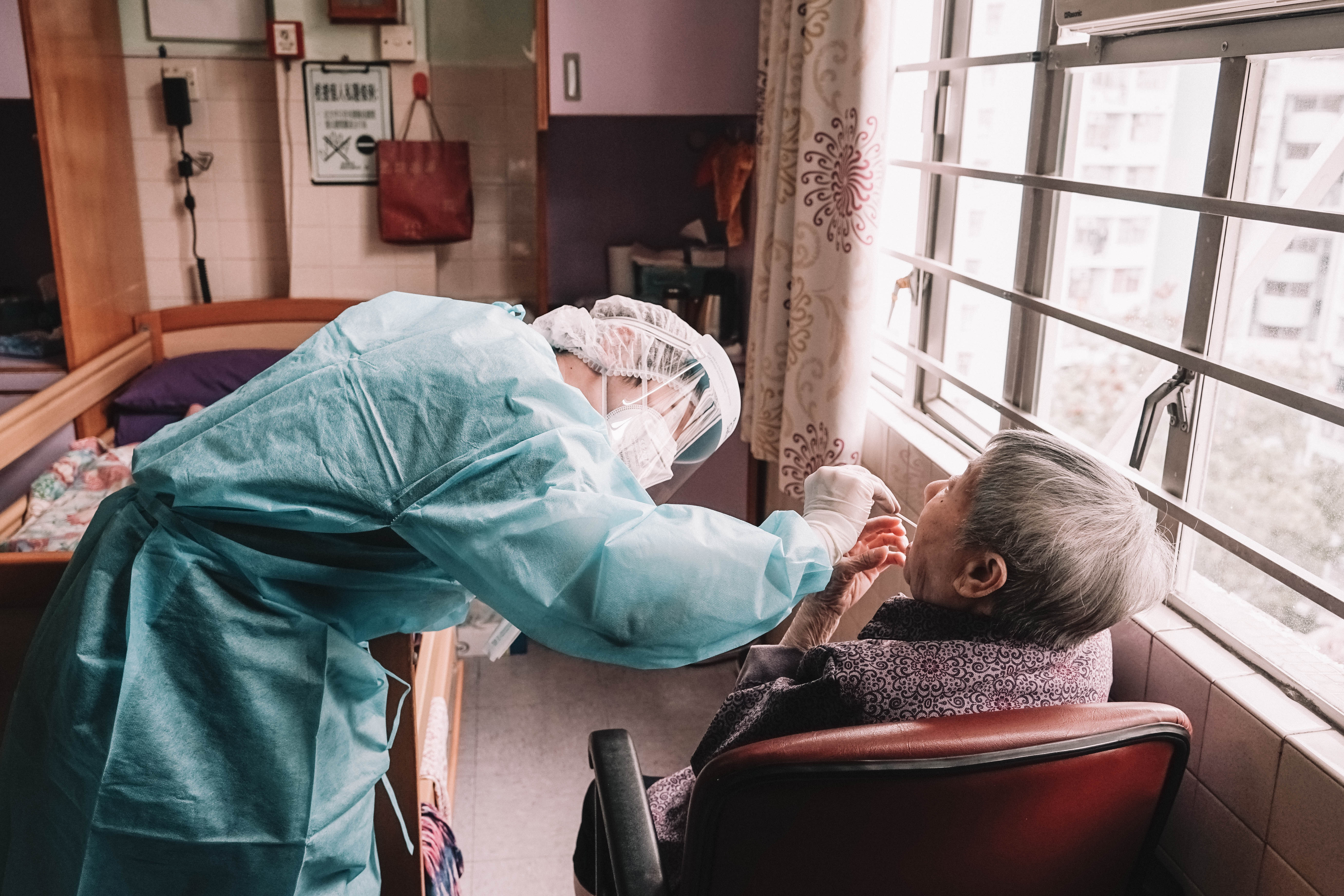 A professionally trained nurse from Evercare collects nasal and throat samples from an elderly at a care home.